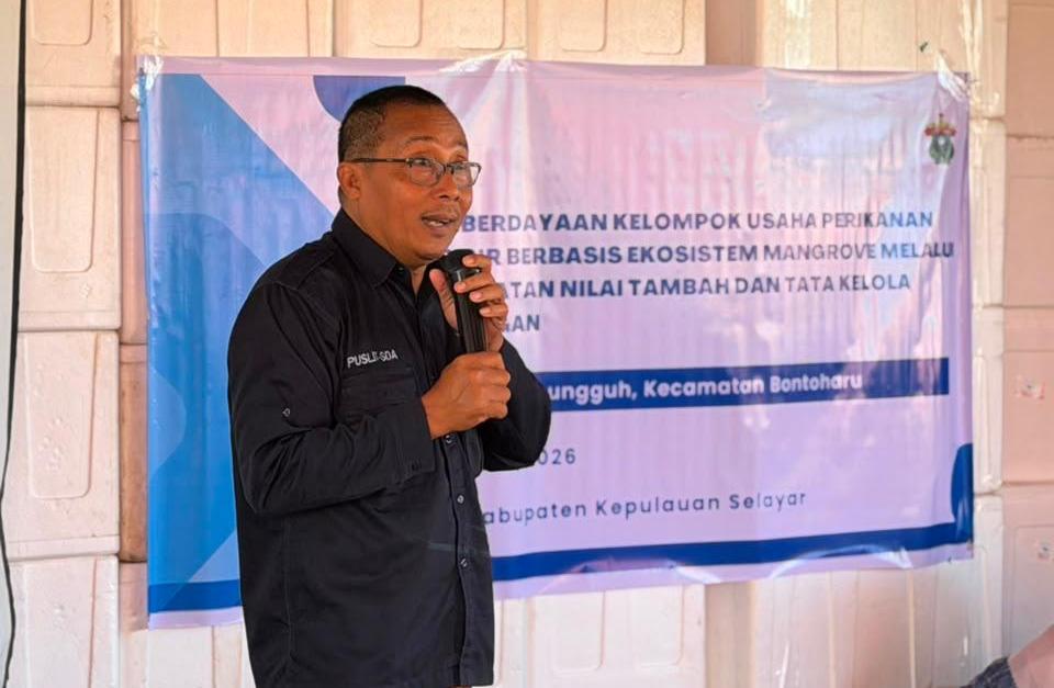 Pria berbicara di depan banner kegiatan perikanan