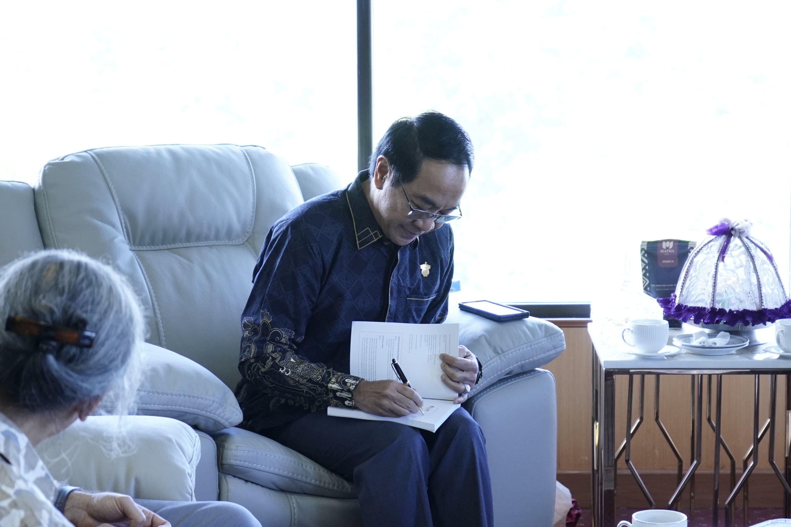 Pria menandatangani dokumen di sofa ruang tamu