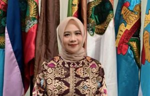 Perempuan berhijab berdiri di depan bendera warna-warni