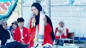 Mahasiswi berhijab mempresentasikan alat dengan mikrofon