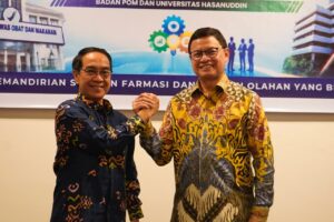 Dua pria berjabat tangan memakai batik