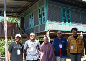 Lima orang berdiri di depan rumah panggung