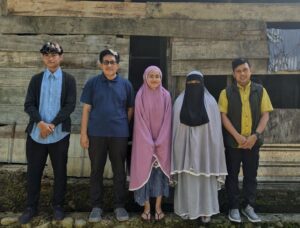 Lima orang berdiri di depan rumah kayu