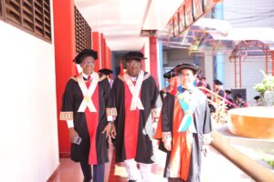 Tiga profesor mengenakan jubah wisuda di kampus