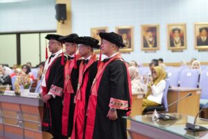 Empat profesor mengenakan toga akademik di aula