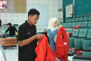 Mahasiswa memeriksa jaket merah di auditorium