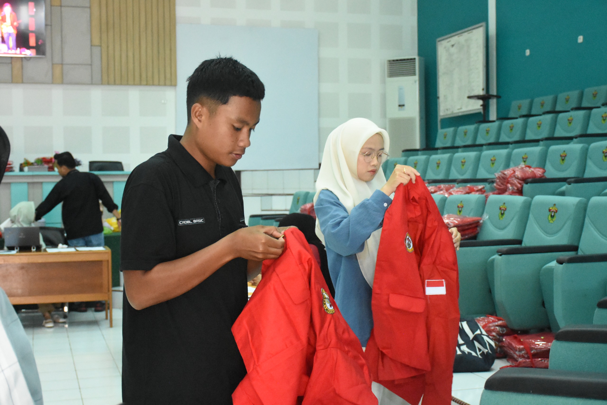 Mahasiswa memeriksa jaket merah di auditorium