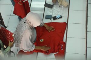 Perempuan melipat seragam merah di lantai