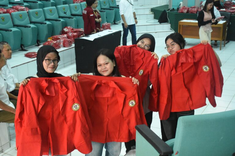 Mahasiswi memegang jaket merah di auditorium kampus