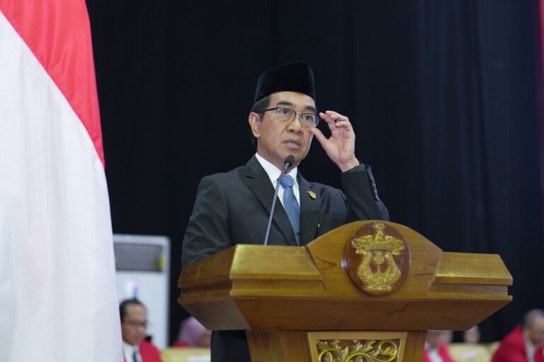 Pria berpeci berpidato di podium resmi