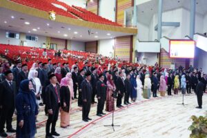 Upacara resmi di auditorium besar dengan peserta berdiri