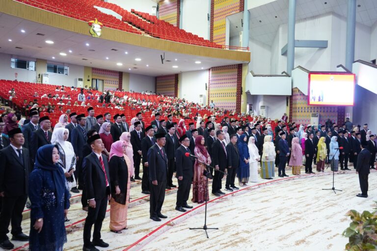 Upacara resmi di auditorium besar dengan peserta berdiri
