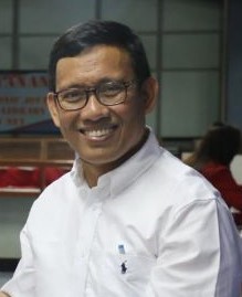 Pria berkacamata tersenyum mengenakan kemeja putih