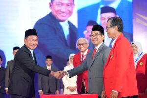 Dua pria bersalaman di acara resmi