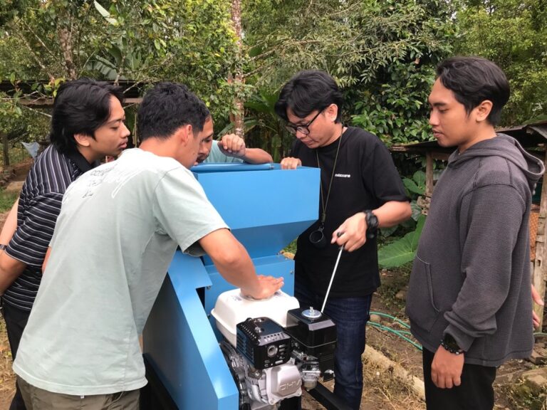 Empat pria memeriksa mesin pertanian biru