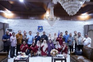 Kelompok orang berpose di ruang resmi