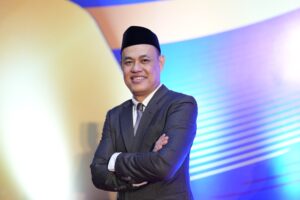 Pria bersetelan jas dan peci tersenyum