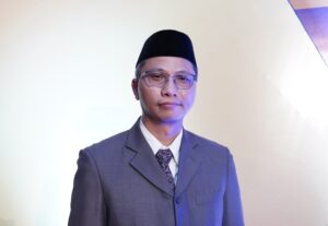 Pria bersetelan jas dan peci hitam