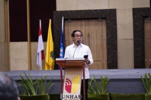 Pria berpidato di podium dengan bendera Indonesia