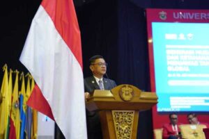 Pejabat berpidato di podium dengan bendera Indonesia