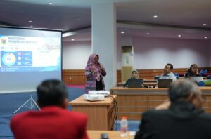 Pemateri mempresentasikan monitoring akreditasi di ruang rapat