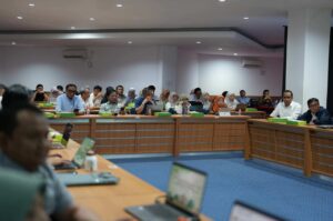 Peserta rapat duduk di ruang konferensi dengan laptop