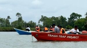 Relawan mengumpulkan sampah di sungai dengan perahu
