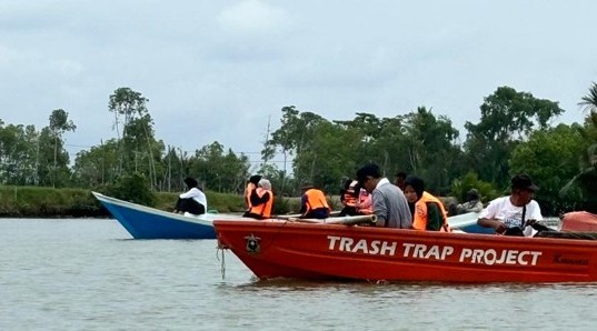 Relawan mengumpulkan sampah di sungai dengan perahu