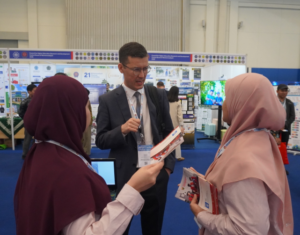 Man discussing brochure with two women at expo