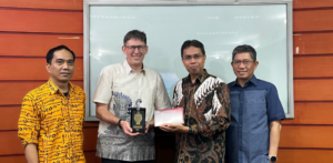 Four men holding award plaque and certificate indoors
