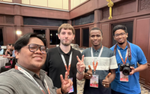 Four men posing with badges at conference