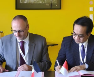 Two officials signing documents with national flags