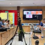 Conference room meeting with video call on screen