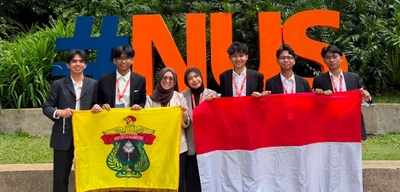 Students holding flags in front of NUS sign