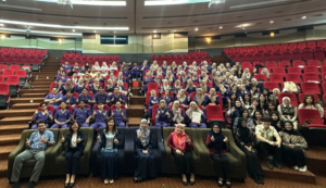 Large group posing in auditorium with red seats