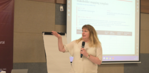 Woman presenting with microphone before projected slide