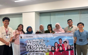 Students holding Summer Medical Exchange Program banner indoors