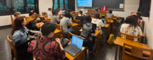 Students attending lecture in classroom with presentation screen