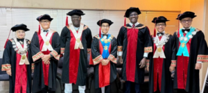 Seven officials in academic regalia posing indoors