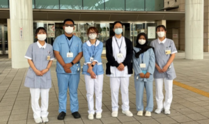 Six masked healthcare workers outside hospital entrance