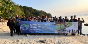 Group holding marine biodiversity course banner on beach