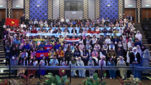 Large international group holding flags in auditorium
