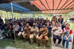 Kelompok warga dan petugas berseragam di bawah tenda