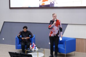 Pria berbicara di acara panel dengan bendera Indonesia