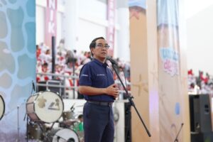 Pria berbicara di mikrofon pada acara indoor
