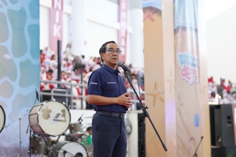 Pria berbicara di mikrofon pada acara indoor