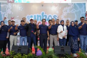 Pejabat dan peserta berpose dengan kepalan tangan di panggung