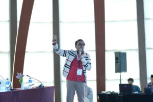 Pembicara memegang mikrofon saat presentasi di konferensi