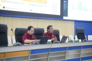 Dua staf mempresentasikan rapat akademik dengan laptop