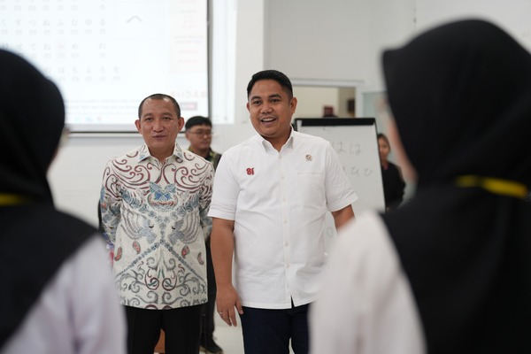 Dua pria berbicara di depan peserta pelatihan berhijab
